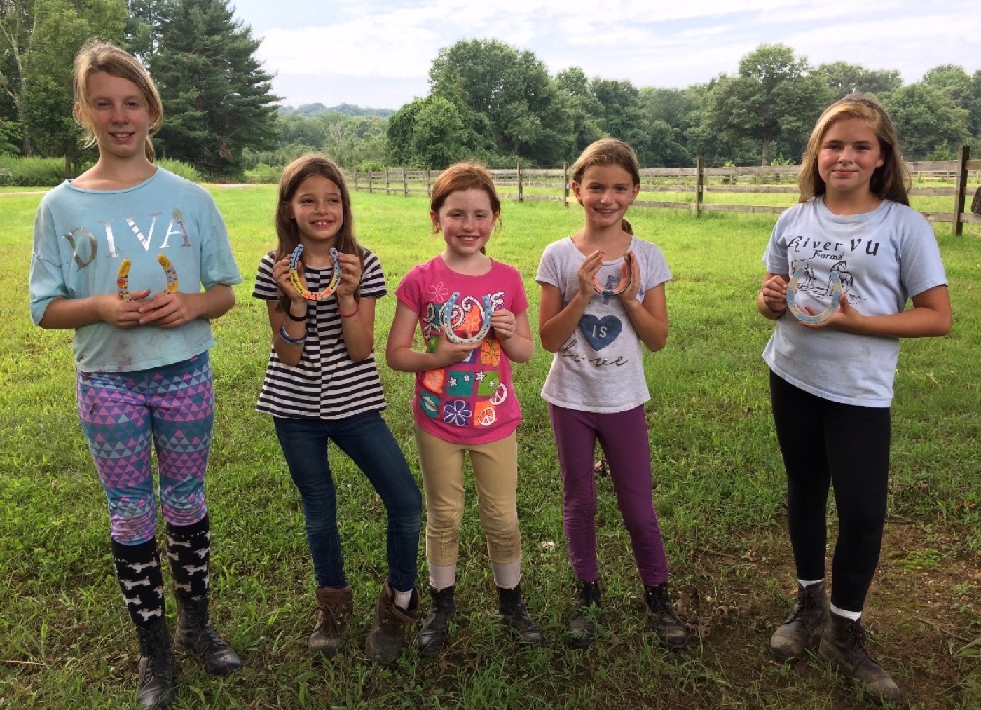 River Vu Farms campers holding painted horseshoes in a pasture